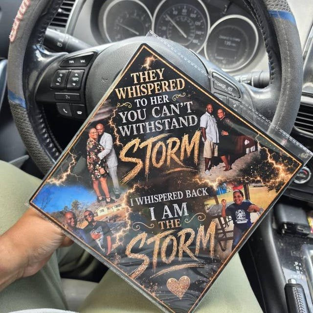 Graduate holding an 'I Am the Storm' photo collage grad cap topper inside a car