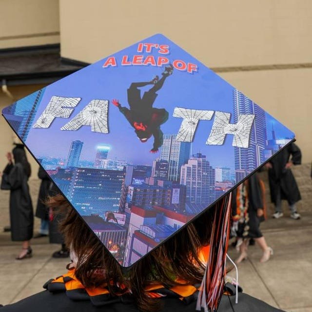 Graduate wearing a Spider-Man 'It's a Leap of Faith' grad cap topper