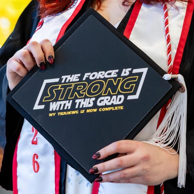 Graduate holding a Star Wars 'The Force Is Strong With This Grad' grad cap topper