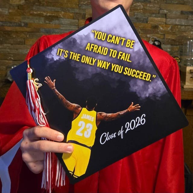 Graduate holding a LeBron James 'You Can't Be Afraid to Fail' Class of 2026 grad cap topper