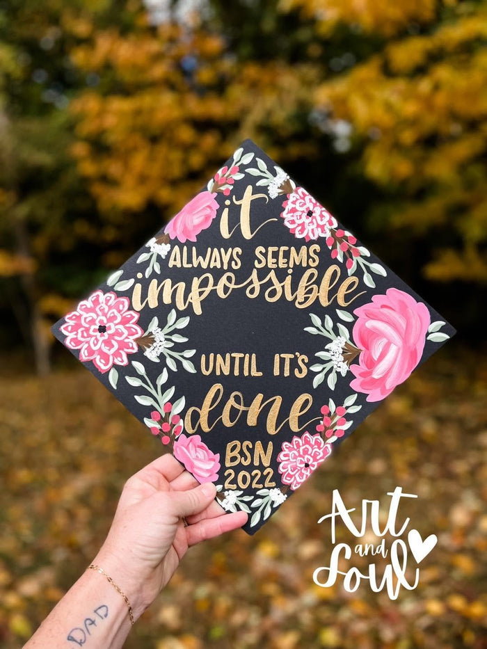 Graduate holding a floral 'It Always Seems Impossible Until It's Done BSN' grad cap topper