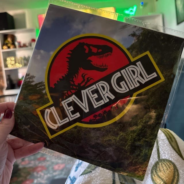 Graduate holding a Jurassic Park 'Clever Girl' grad cap topper