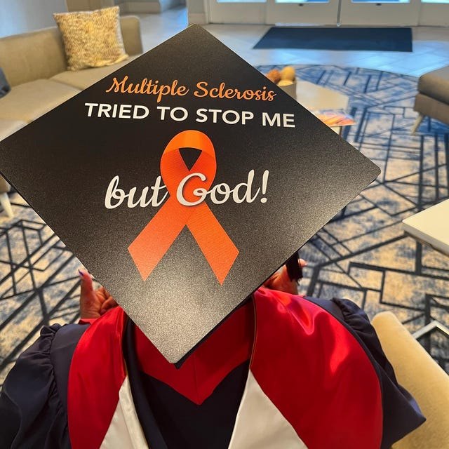 Graduate holding a 'Multiple Sclerosis Tried to Stop Me But God' orange ribbon grad cap topper