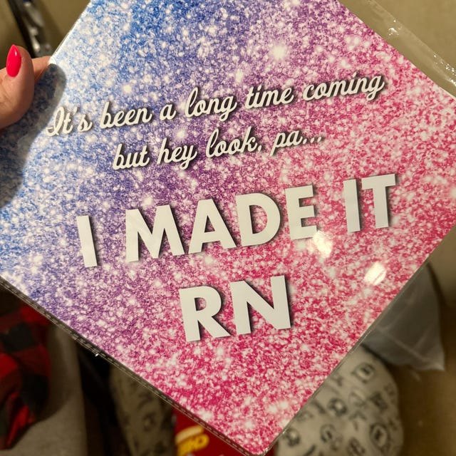 Graduate holding a pink glitter 'I Made It RN' nursing grad cap topper