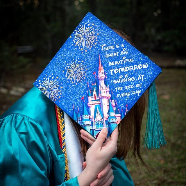 Graduate holding a Disney castle 'Great Big Beautiful Tomorrow' grad cap topper