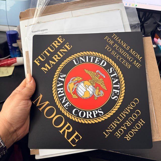Graduate holding a 'Future Marine Moore' US Marine Corps grad cap topper