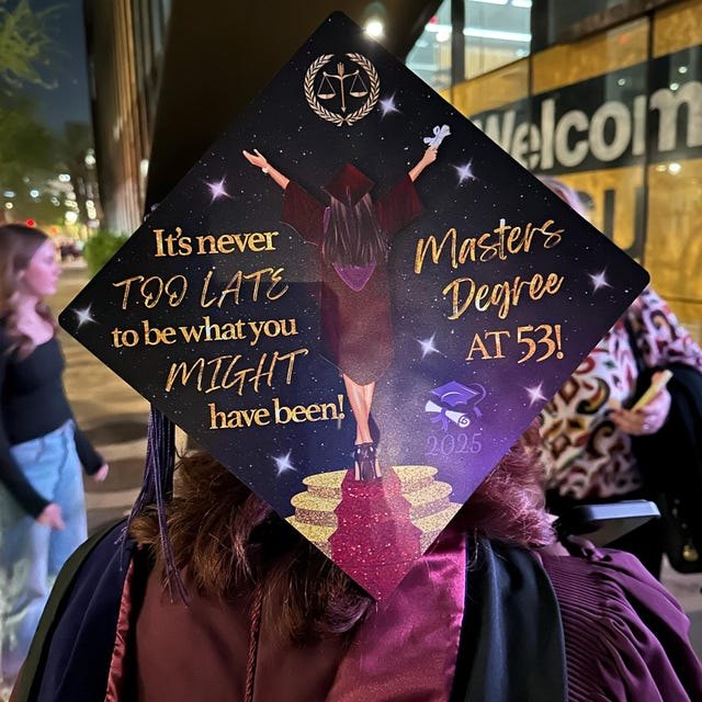 Graduate wearing an 'It's Never Too Late — Master's Degree at 53' grad cap topper