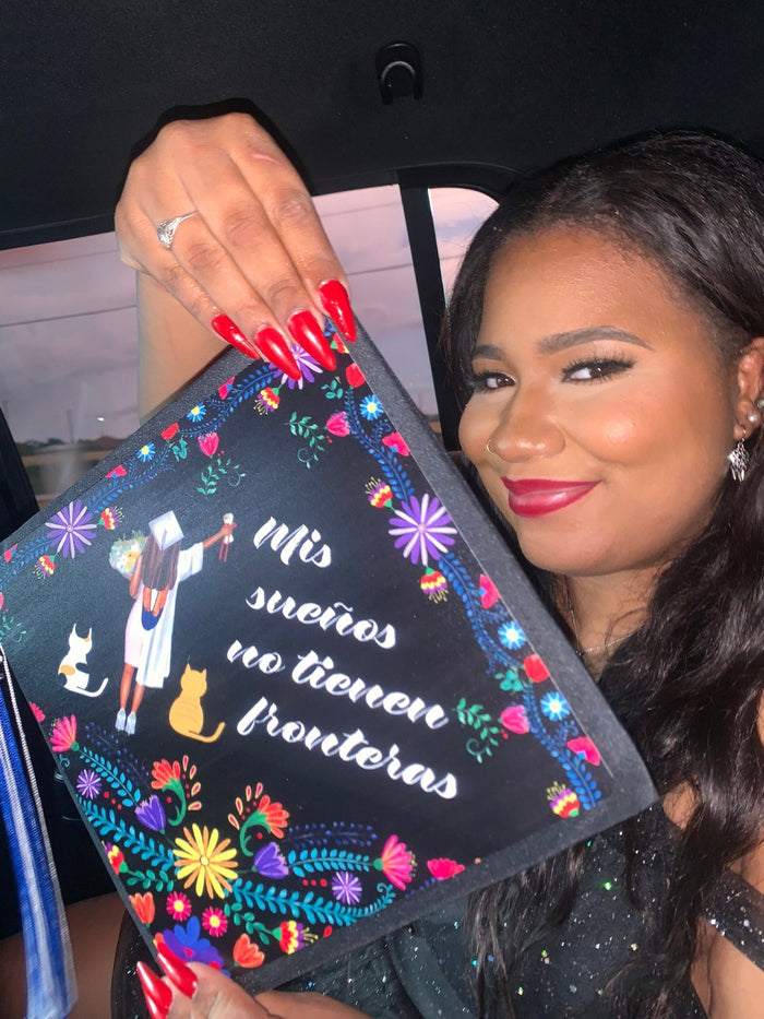 Woman in car holding Mis sueños no tienen fronteras floral cap