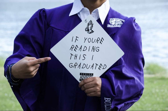 Graduate in purple gown holding If Youre Reading This I Graduated cap