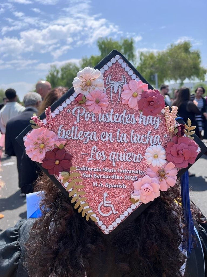 Graduate wearing pink floral Spanish quote cap, back view