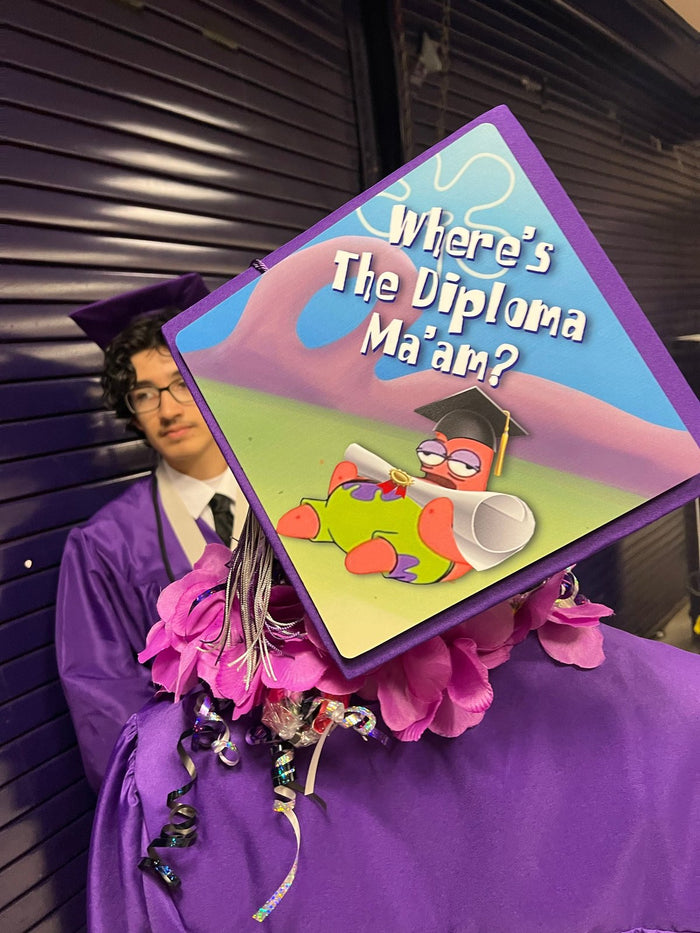 Graduate holding Wheres The Diploma Maam Patrick topper with lei