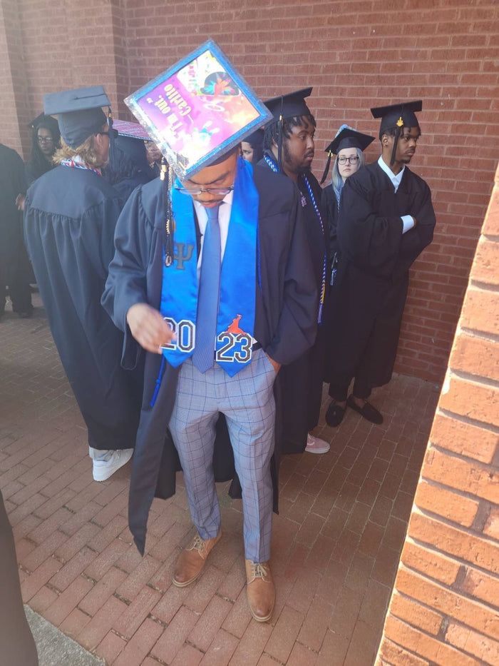 Graduate wearing colorful topper with classmates behind