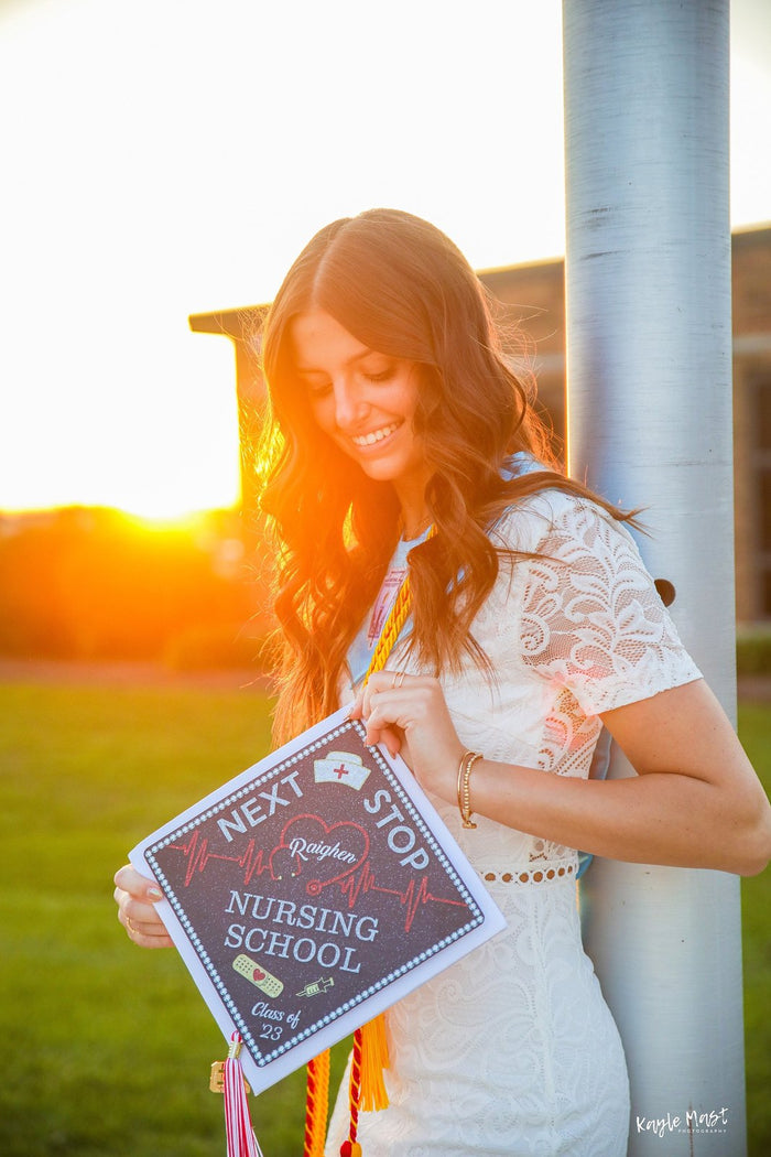 Woman holding Next Stop Nursing School topper at sunset