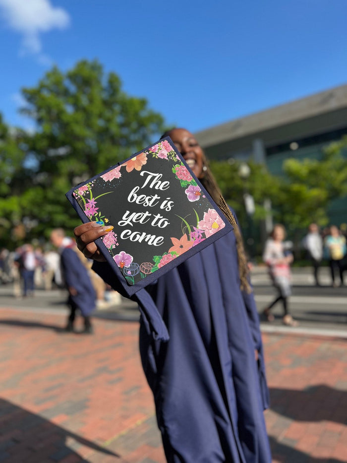 Graduate holding The Best Is Yet To Come floral topper