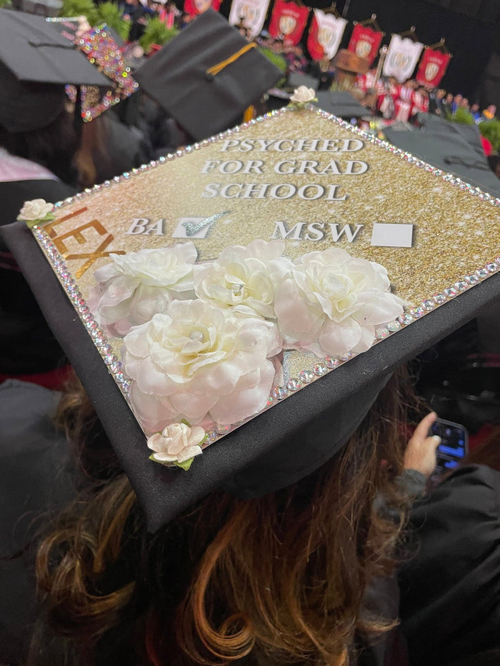 Graduate wearing Psyched for Grad School MSW cap with roses at ceremony