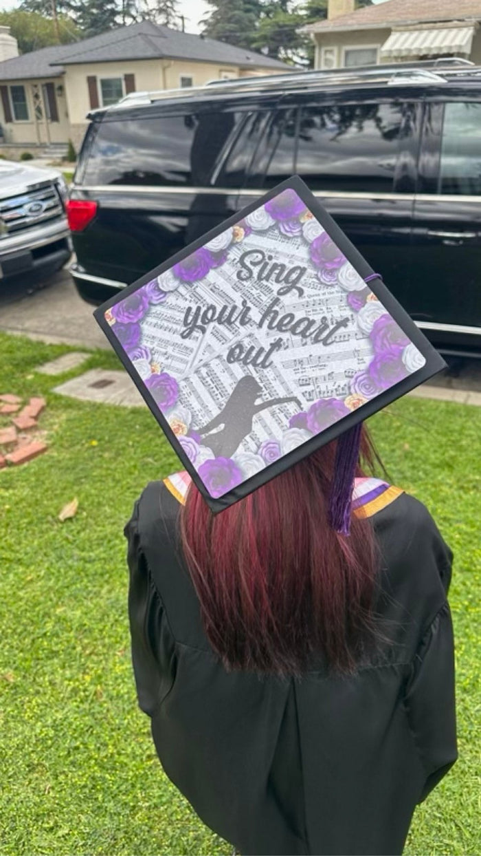 Graduate wearing Sing Your Heart Out purple cap, back view