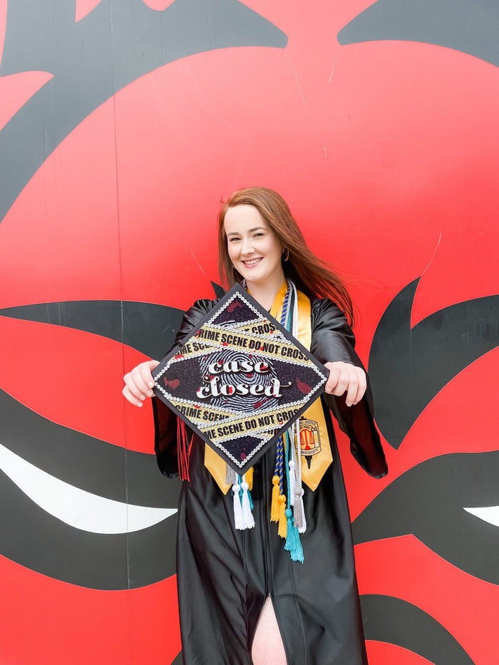 Graduate holding Case Closed law cap by mural