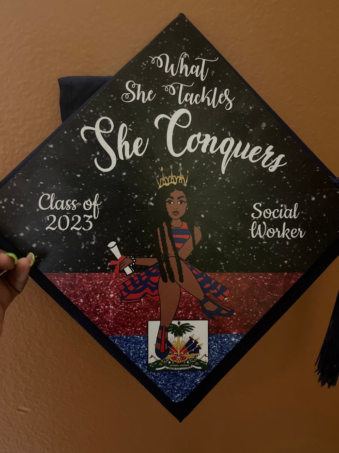 Fingers holding What She Tackles She Conquers social worker topper