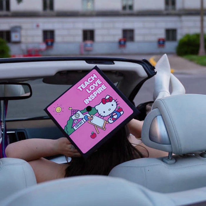 Woman in convertible holding Hello Kitty Teach Love Inspire cap