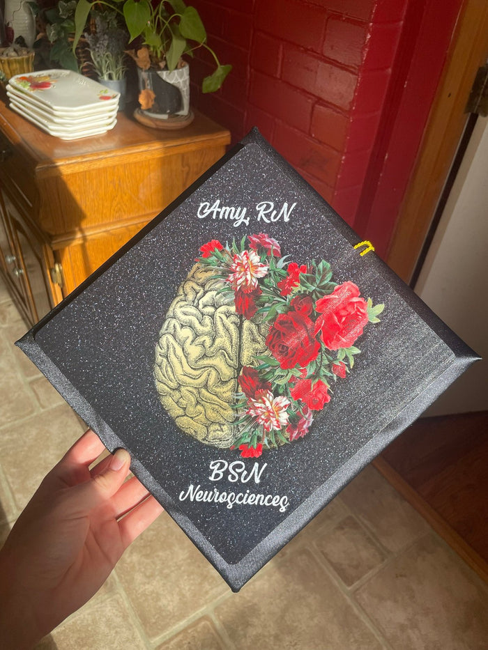 Hand holding Amy RN brain and roses topper