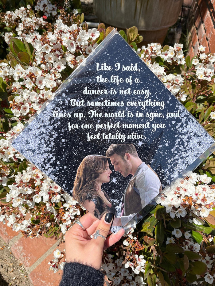Hand holding dancer quote topper over flowering bush