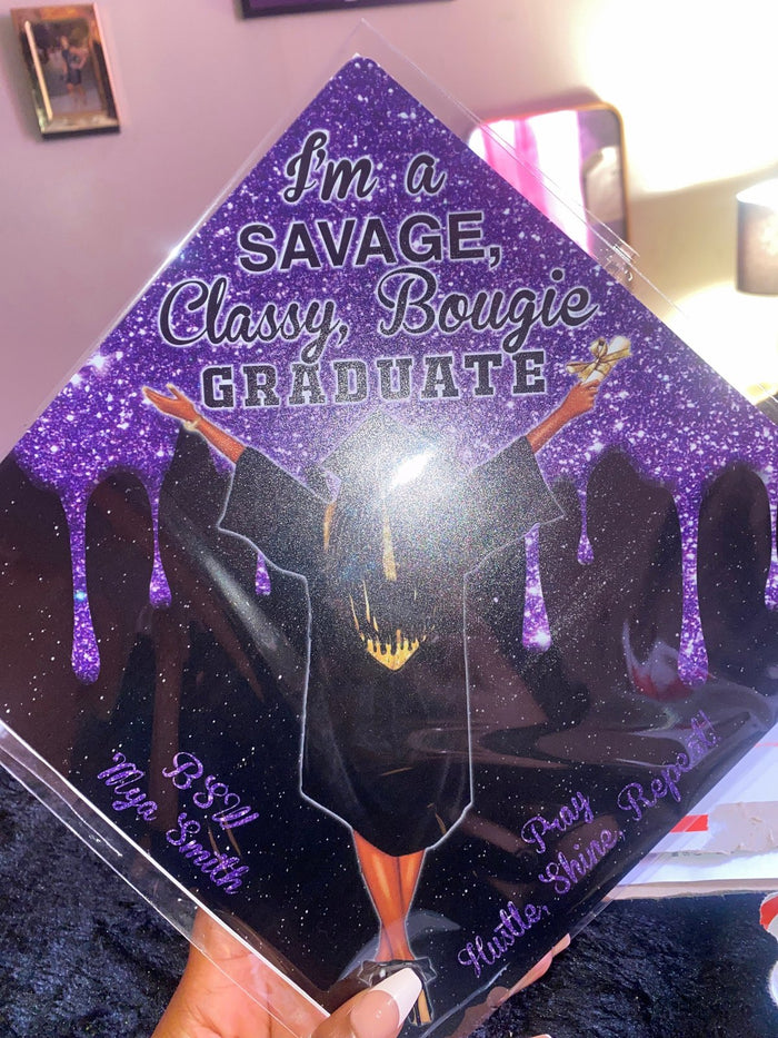 Hand holding purple Savage Classy Bougie Graduate topper D Smith