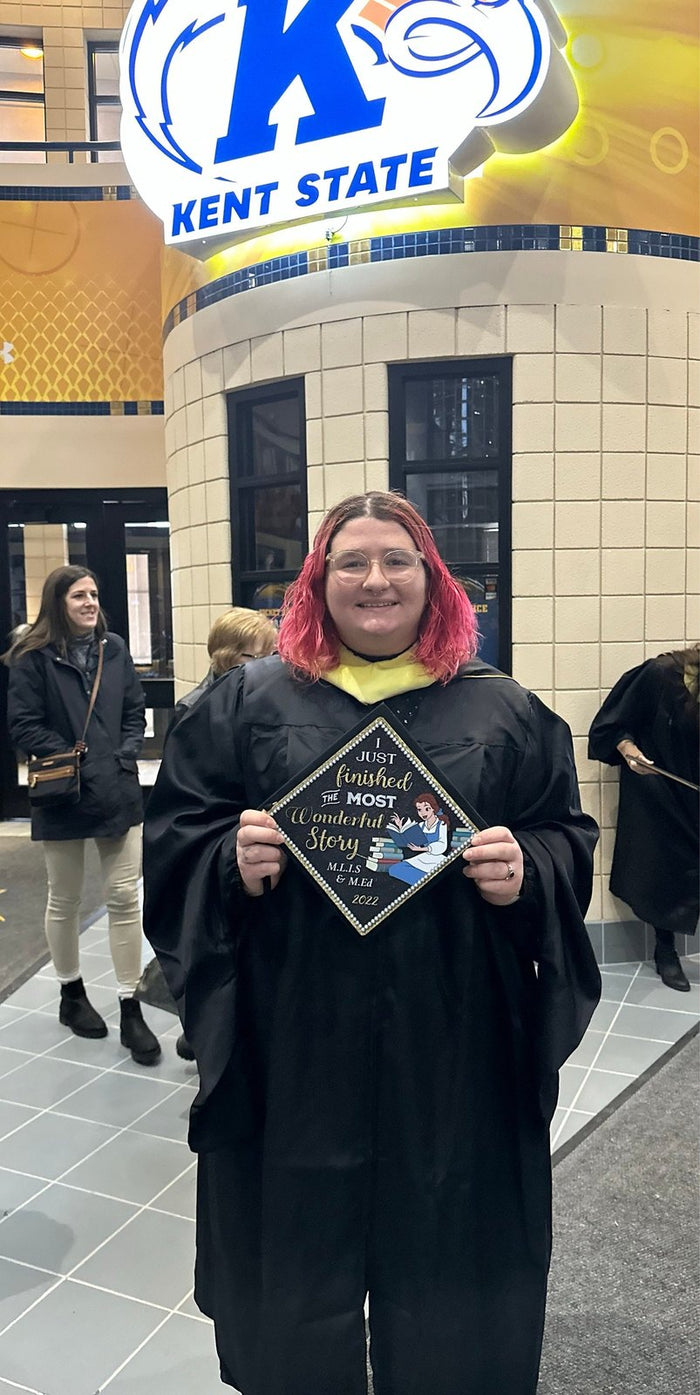 Kent State graduate holding Belle Most Wonderful Story MLIS cap