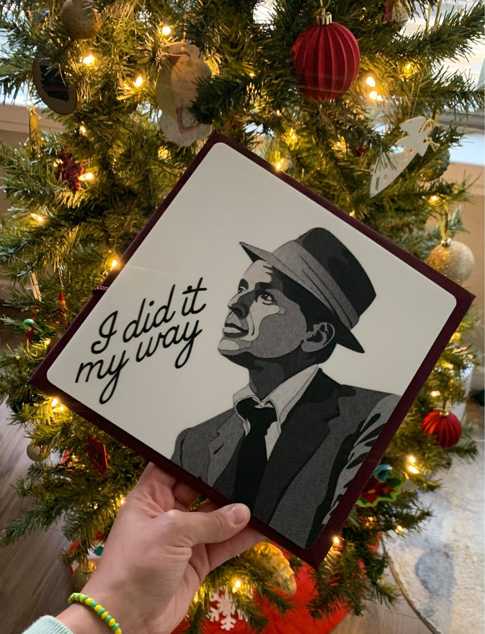 Hand holding Sinatra I Did It My Way topper by Christmas tree