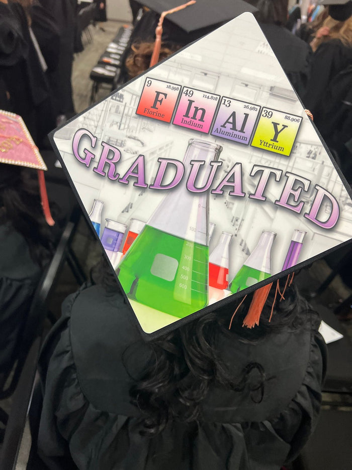 Graduate wearing Finally Graduated periodic table cap at ceremony
