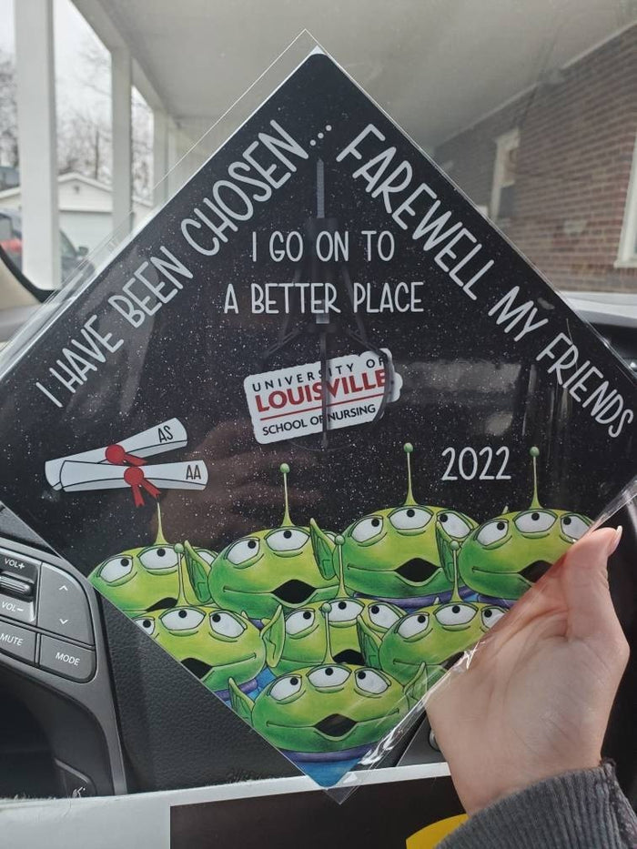 Hand holding Toy Story aliens Louisville Farewell topper in car