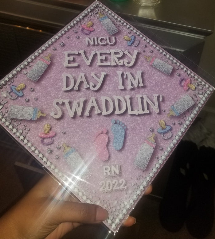Hand holding NICU Every Day Im Swaddlin topper