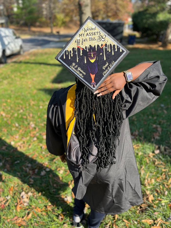 Graduate holding decorated cap over face outdoors