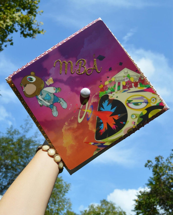 Arm holding Kanye MBA topper against sky