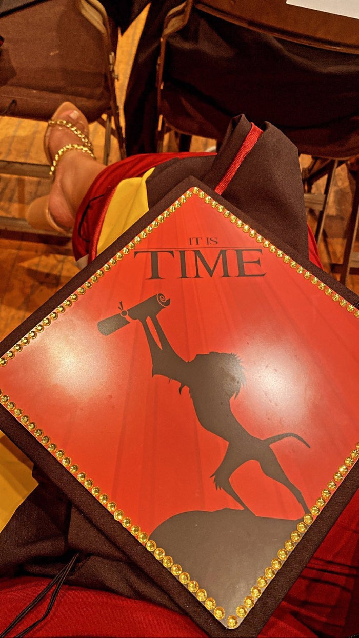 Lion King It Is Time cap resting on graduates lap at ceremony