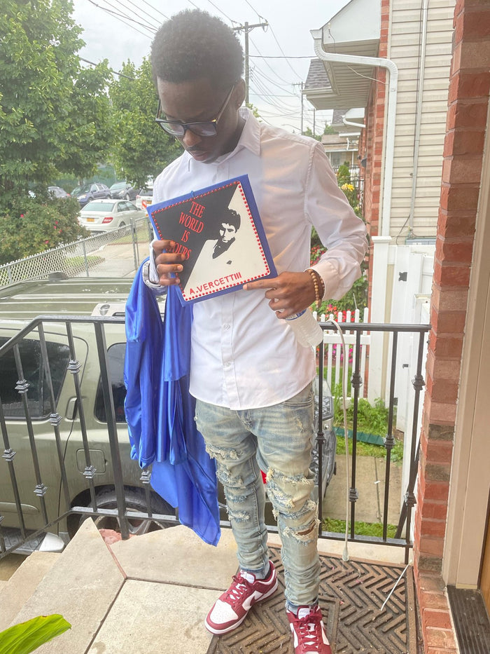 Young man holding Scarface topper and gown on porch