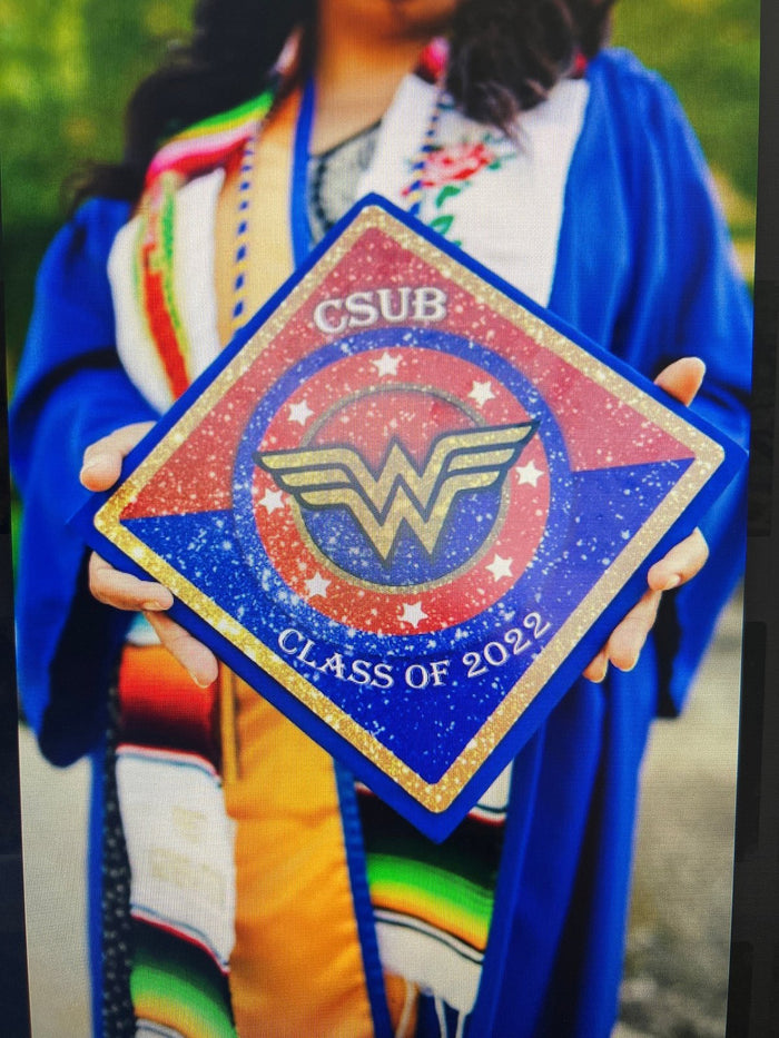 Graduate holding CSUB Wonder Woman cap