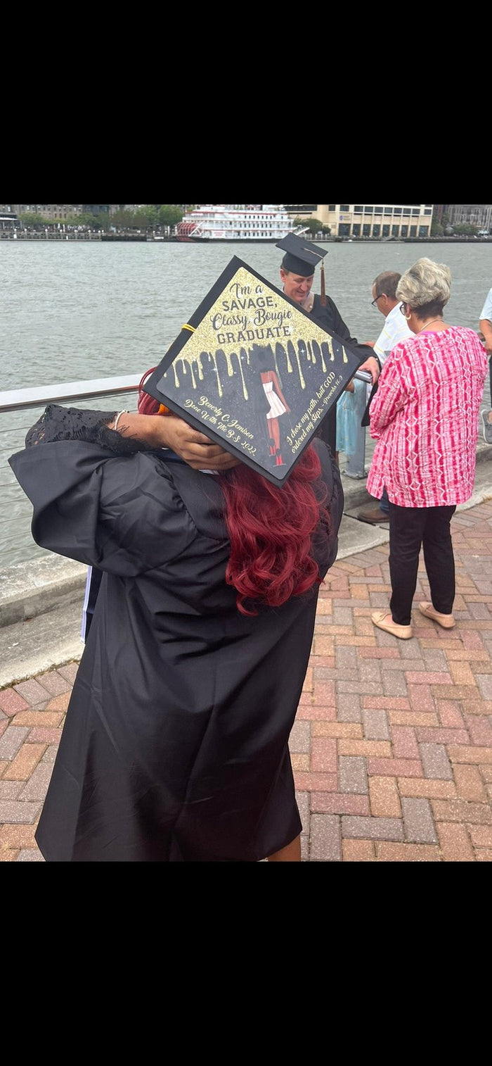 Graduate holding cap over face by river, story frame