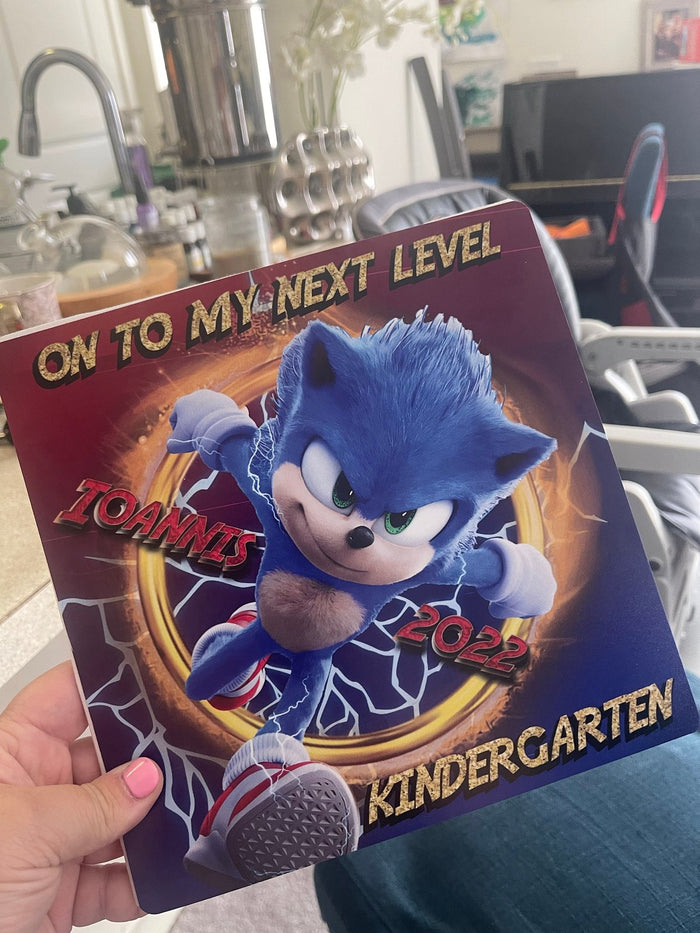 Hand holding Sonic On To My Next Level Kindergarten topper