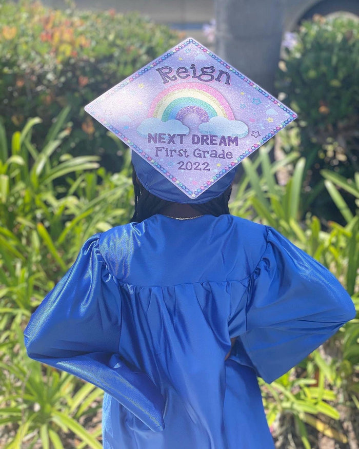 Child in blue gown wearing Reign Next Dream First Grade cap