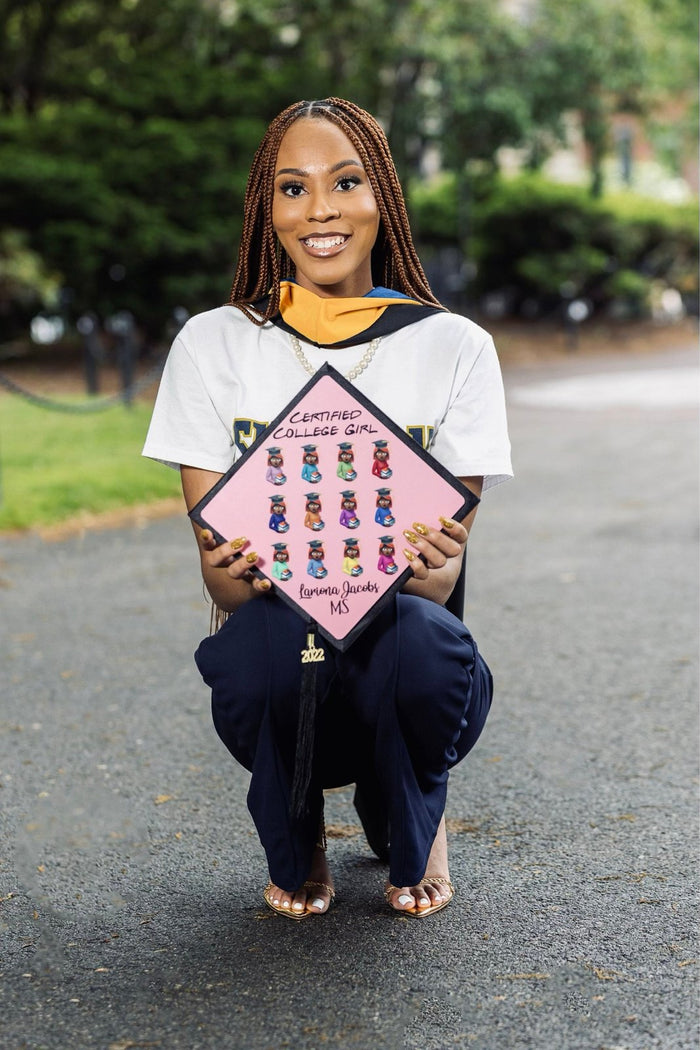 Graduate kneeling holding pink gummy bear cap
