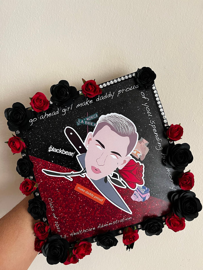 Hand holding blackbear Make Daisy Proud topper with roses