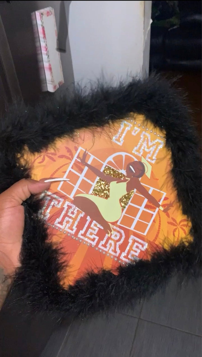 Hand holding Im There Tiana cap with feather trim