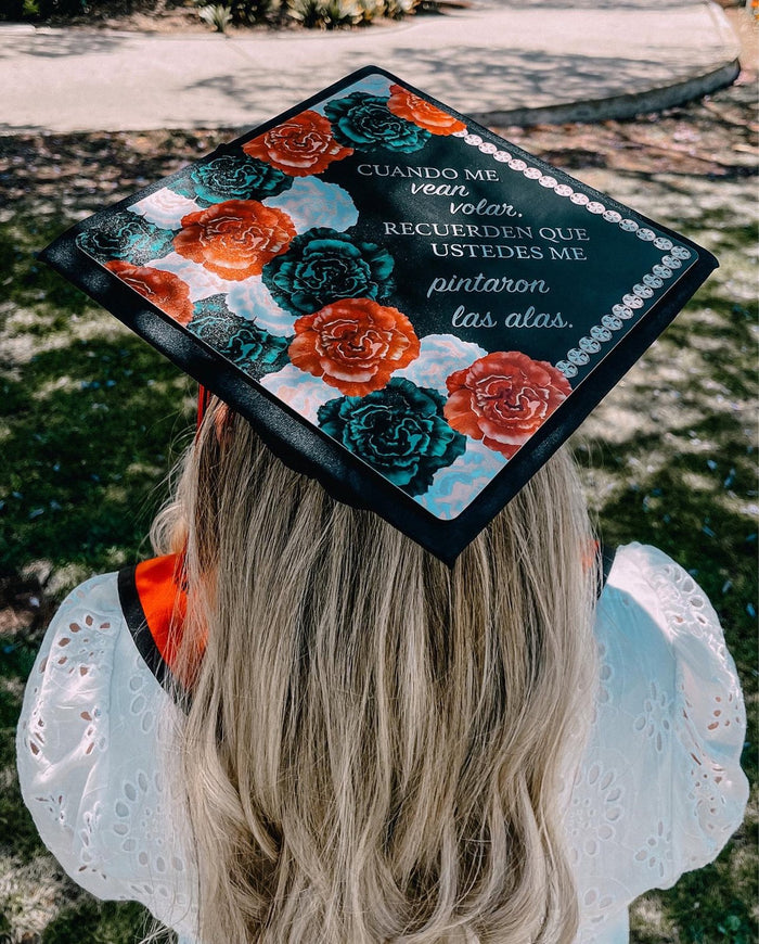 Graduate wearing floral Spanish quote cap, back view