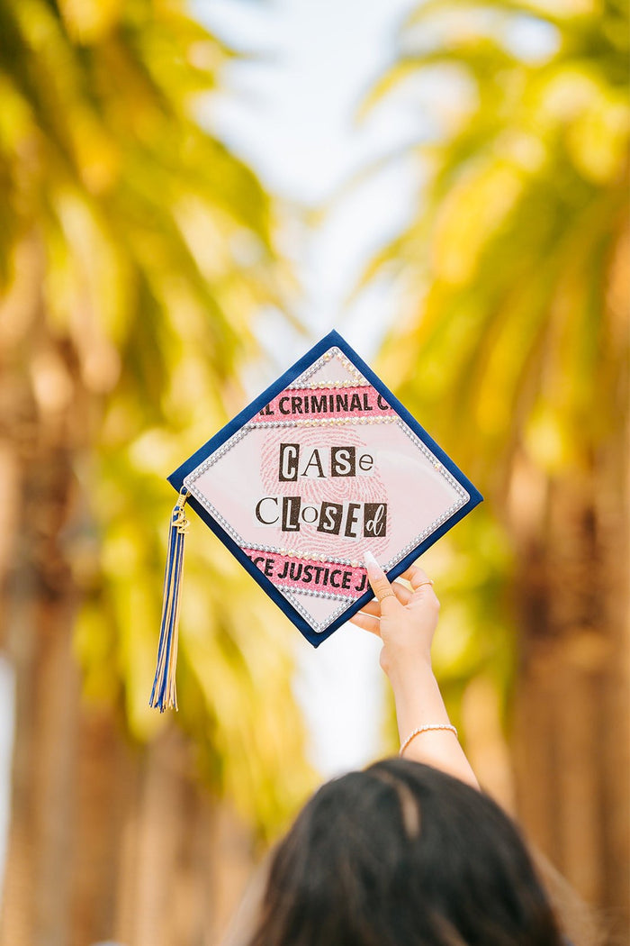 Graduate holding Case Closed criminal justice cap outdoors