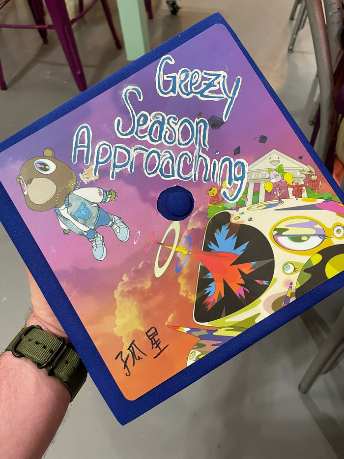Hand holding Kanye Greezy Season Approaching cap