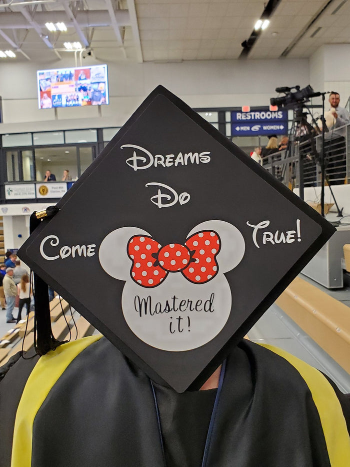 Graduate wearing Minnie Dreams Do Come True cap at airport
