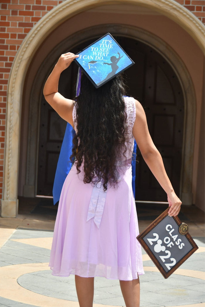 Graduate holding Tiana Its Time To See What I Can Do cap at archway