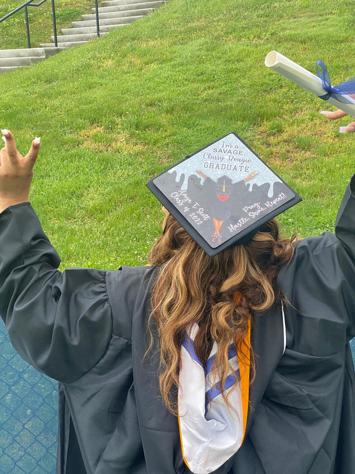 Graduate wearing photo cap holding diploma on lawn, back view