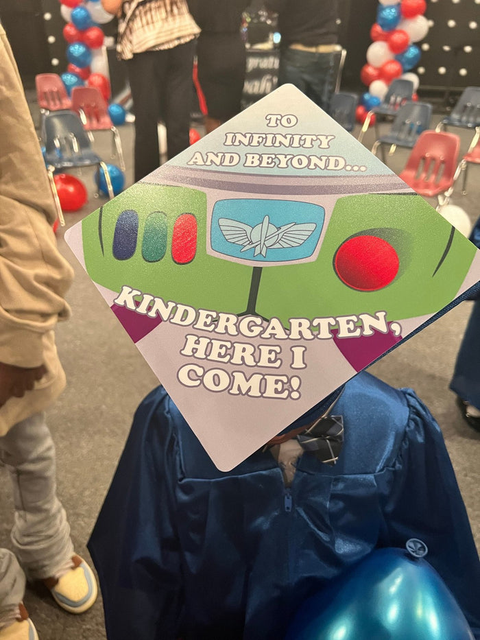 Child in blue gown wearing Buzz Lightyear Kindergarten cap