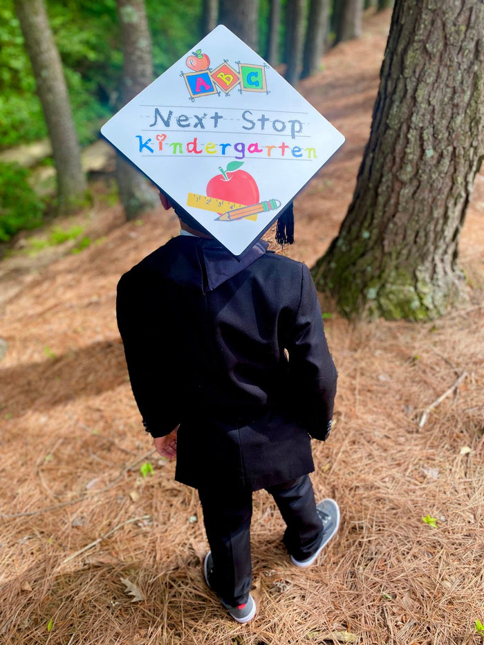 Child wearing Next Stop Kindergarten cap in woods